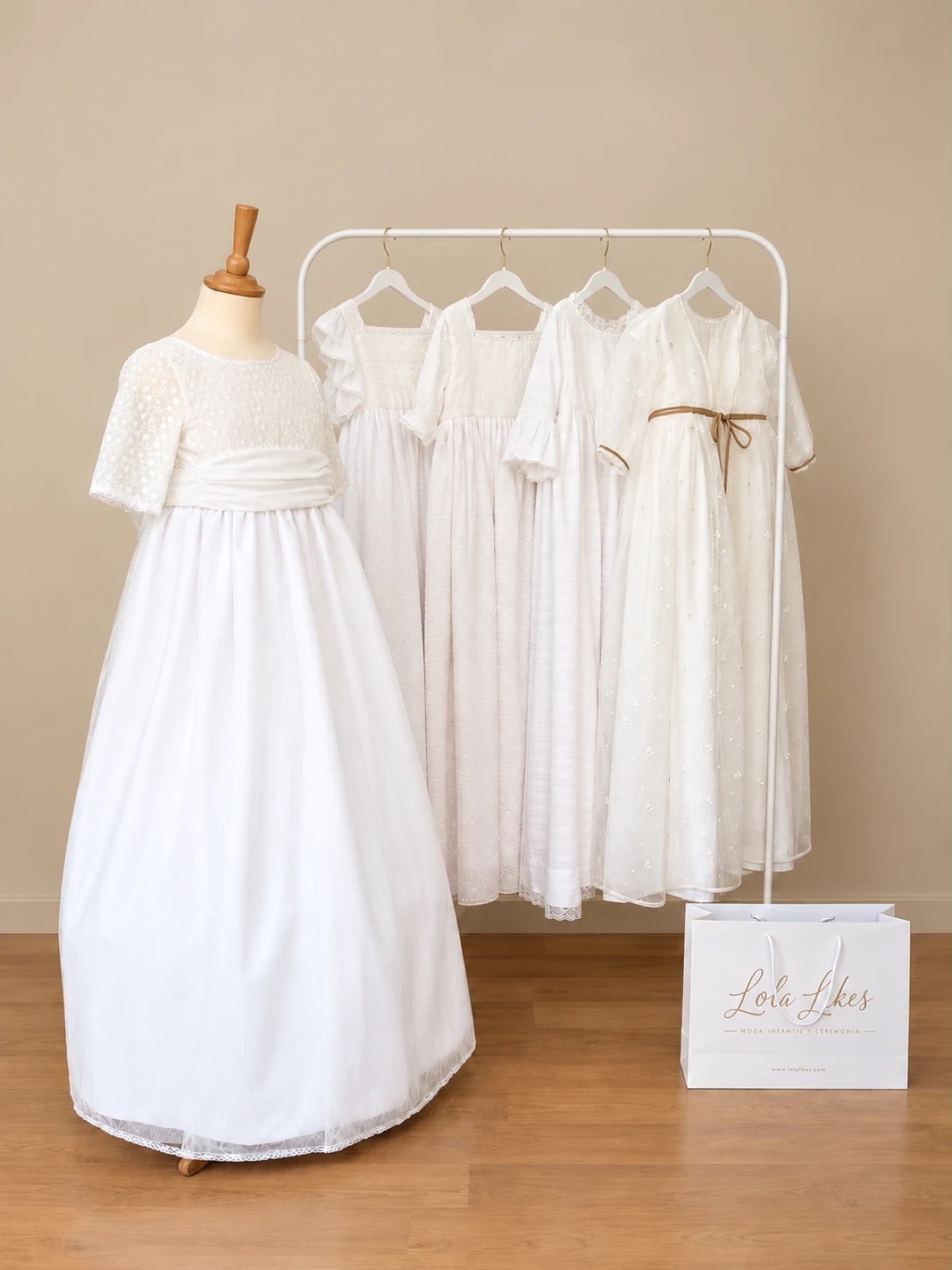 Colección de vestidos de comunión 2027 de Lola Likes en perchero y maniquí